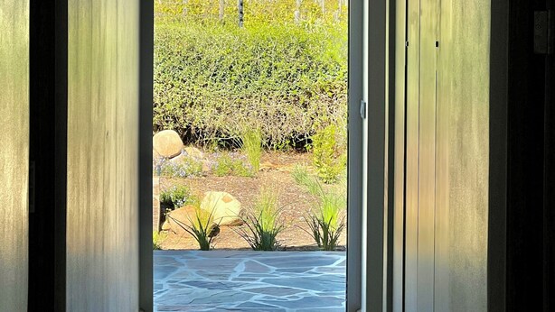 A hallway leading to a vineyard with mountains in the background.