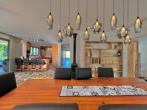 A modern dining area with a wooden table, black chairs, and hanging pendant lights.