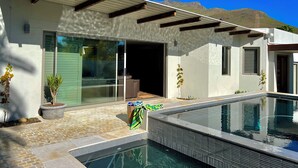 A modern house with a pool, large sliding glass doors, and a pergola.