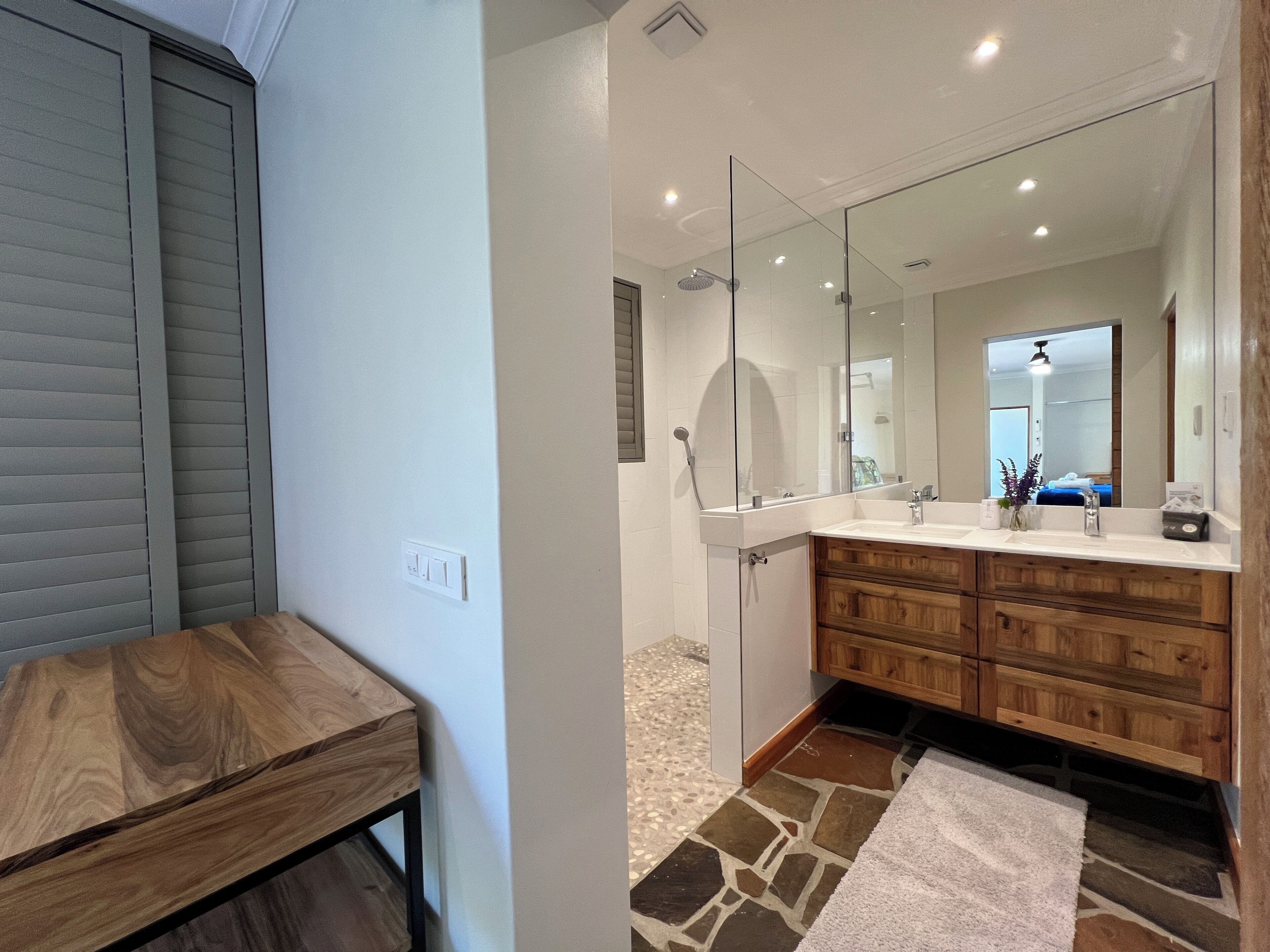 A bathroom with a wooden vanity, a large mirror, and a shower area.