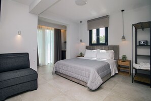 A modern bedroom with a bed, bedside tables, a grey sofa, and a window with curtains.