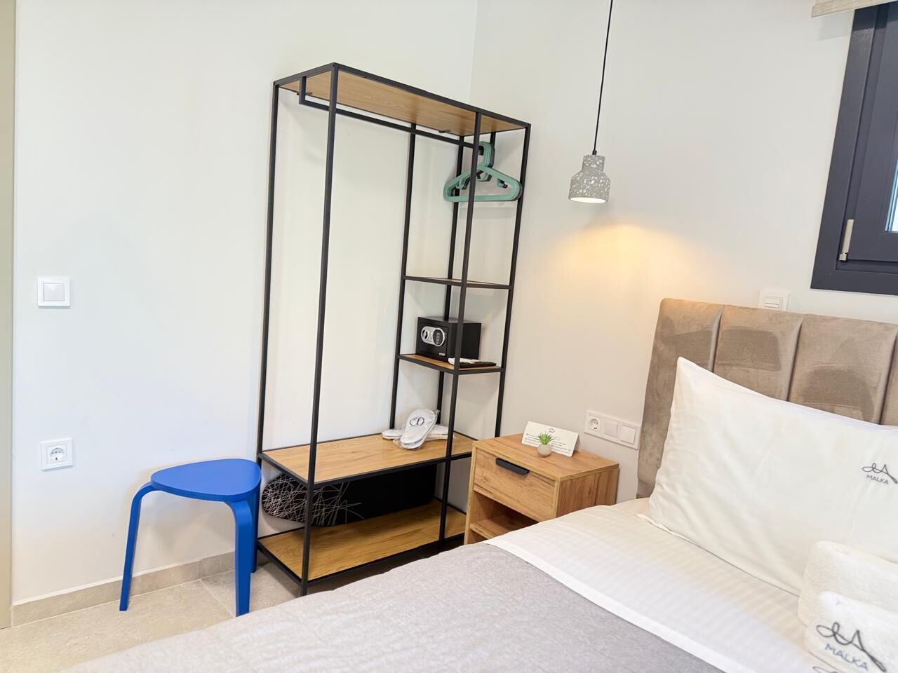 Un dormitorio con una cama, un escritorio con una silla, una lámpara colgante y un armario.