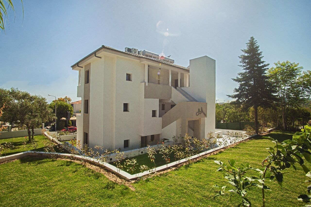 Un immeuble moderne à plusieurs étages, doté d’un toit plat, d’un escalier central et d’un petit espace jardin.