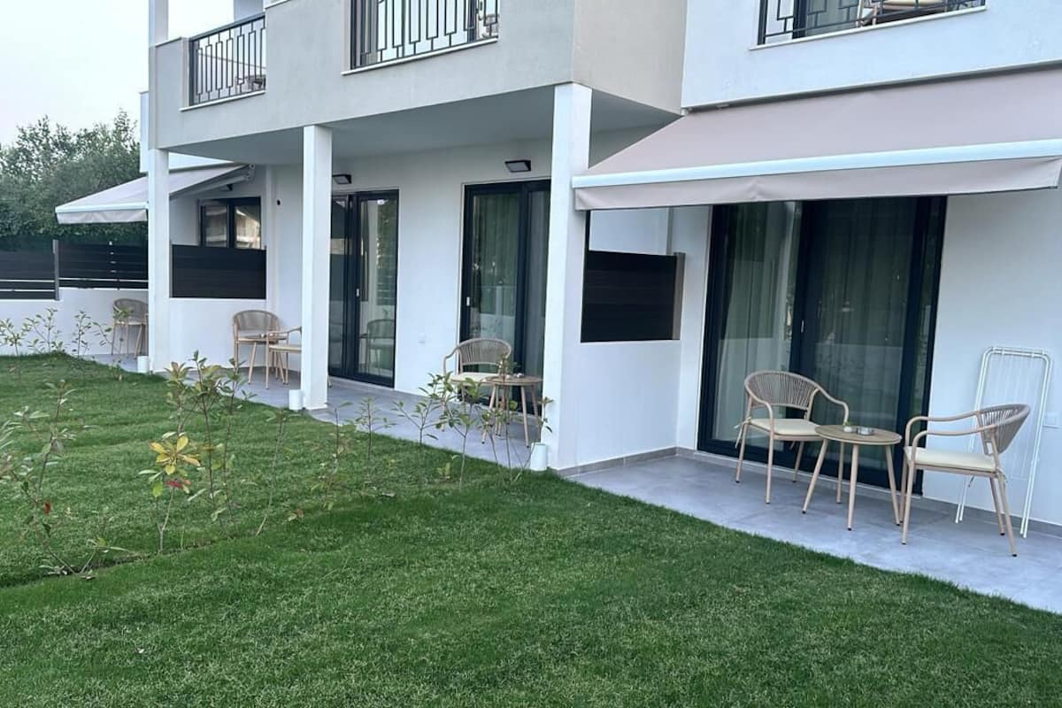 A modern two-story building with a covered patio area, outdoor seating, and a well-maintained lawn.
