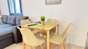 A dining area with a table, chairs, a potted plant, and a remote control. - MALKA PREMIUM SUITES (Kassandra)