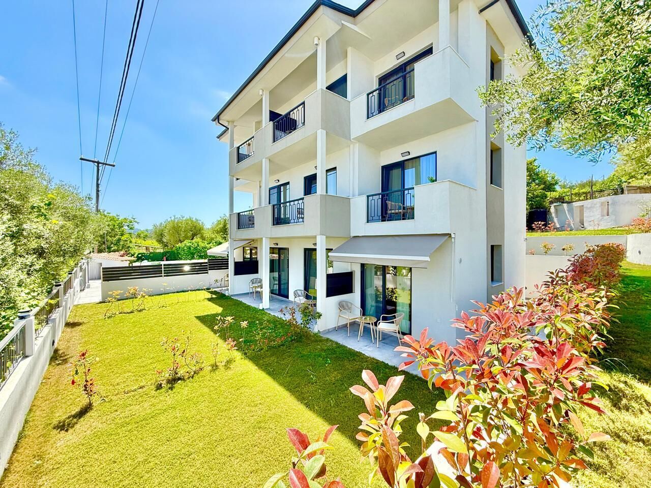 A multi-story building with balconies, a well-maintained lawn, and outdoor seating.
