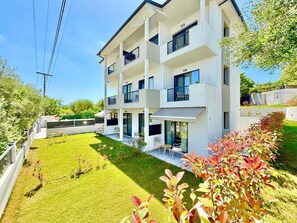 A multi-story building with balconies, a well-maintained lawn, and outdoor seating.