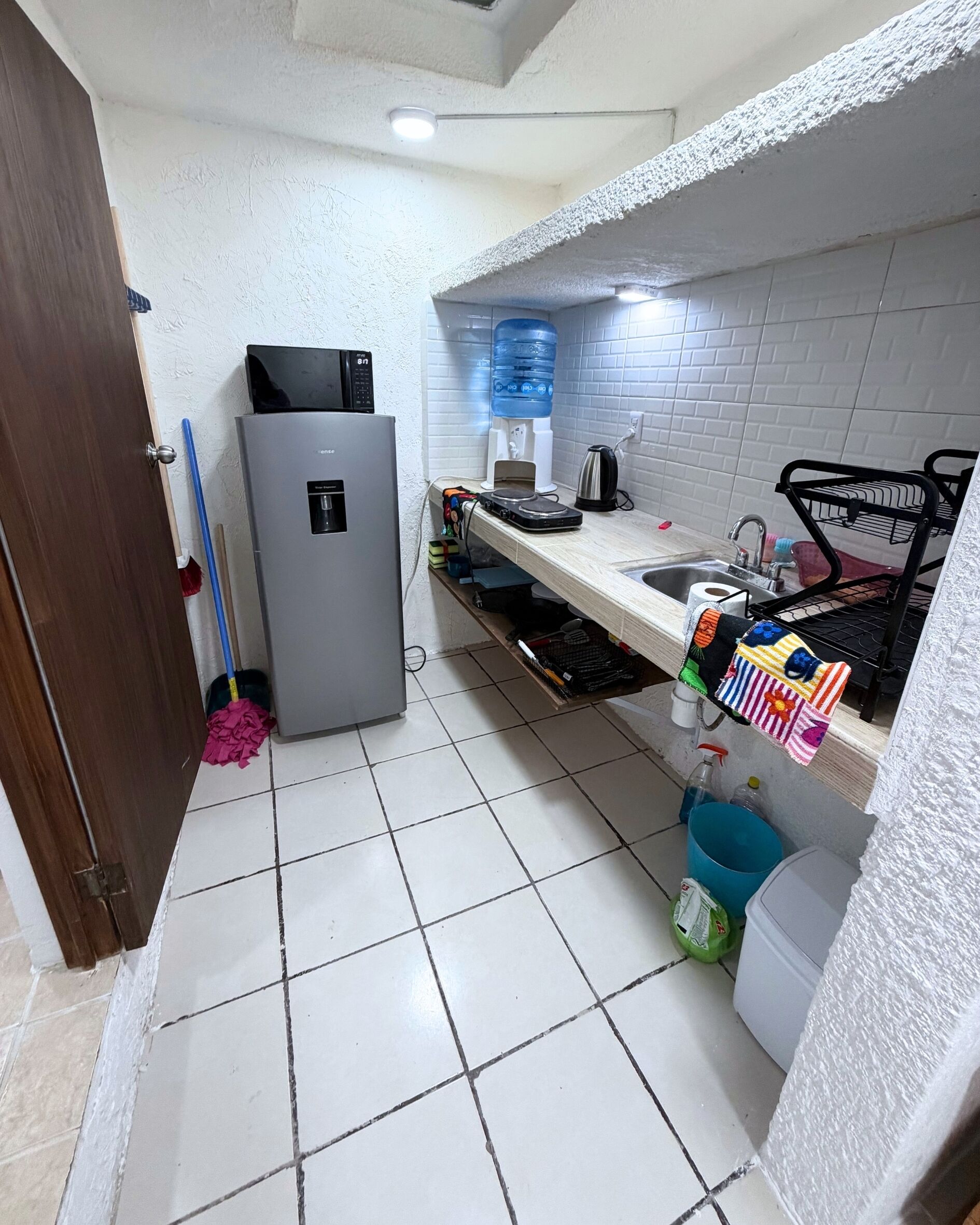 Una cocina compacta con refrigerador, pileta y microondas.