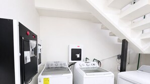 Una sala de lavandería con dos lavadoras, un secador y un cuarto de servicios que incluye un calentador de agua.