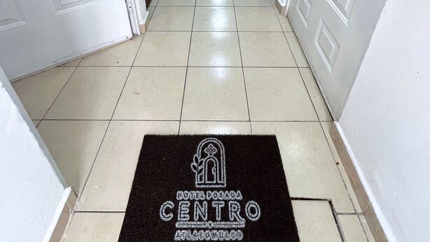 Pasillo de hotel con un felpudo en la entrada que muestra el nombre del hotel y su número de contacto.
