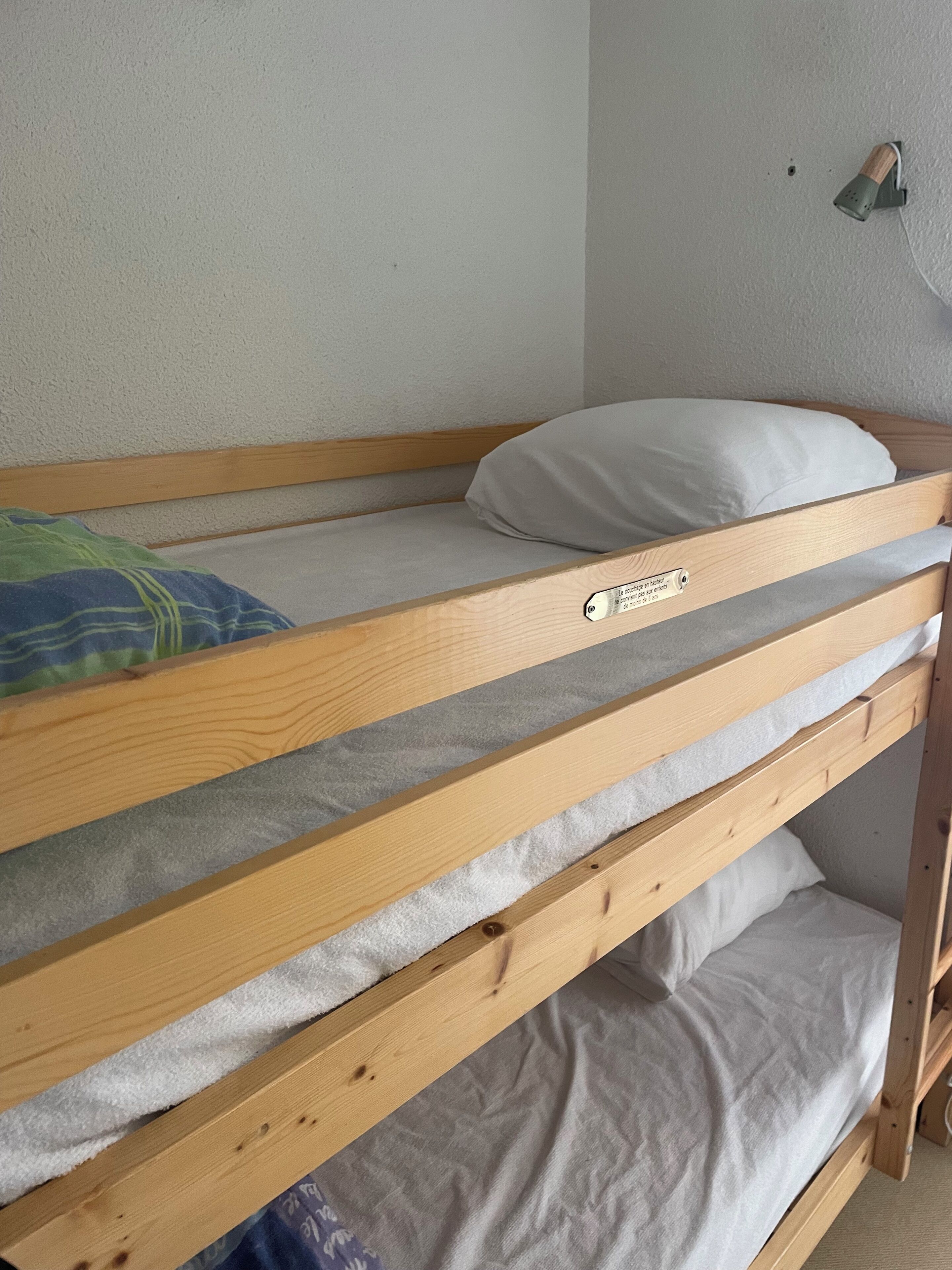 En køjeseng med pude og vægmonteret lampe.