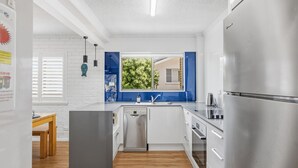 Eine moderne Küche mit eingebautem Geschirrspüler, Edelstahlgeräten und einem Fenster mit Blick auf Grünflächen.