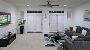 A living room with a TV, sofa, coffee table, and a ceiling fan.
