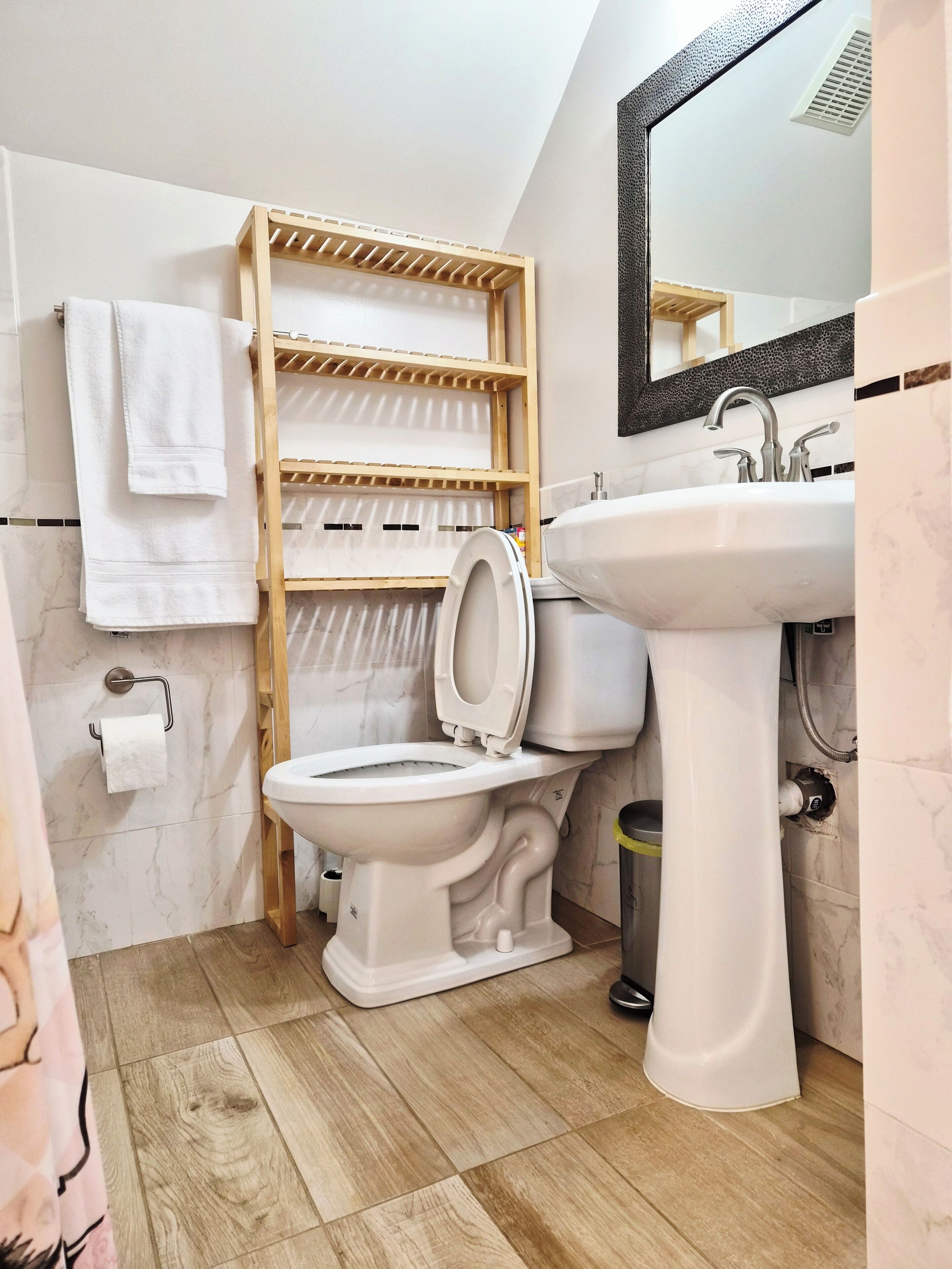 Bagno con WC, lavandino, mensola in legno e specchio.