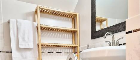 Bagno con WC, lavandino, mensola in legno e specchio.