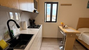 Een kleine keuken met een spoelbak, kookplaat en raam.