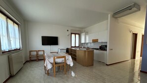 Een ruime keuken met een eethoek, een flatscreen televisie aan de muur en een groot raam dat voor natuurlijk licht zorgt.