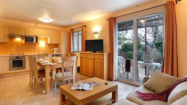 Un espacio habitable compacto con kitchenette, comedor y un sofá con vistas.
