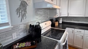 A modern kitchen with white cabinets, a black countertop, a built-in stove, and a decorative wall piece. - STEPS TO THE BEACH
WELCOME TO PARADISE (Mexico Beach)