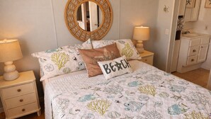 A bedroom with a bed, two bedside tables, a round mirror, a dresser, and a nightstand. - STEPS TO THE BEACH
WELCOME TO PARADISE (Mexico Beach)