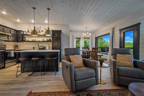 A modern kitchen with dark cabinetry, a central island, bar stools, and pendant lighting. - New Listing! Views, Game Rm, Theater, Fire Pit! (Gatlinburg)