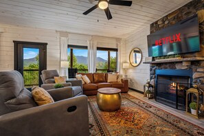 A living room with a fireplace, a television, and a view of mountains. - New Listing! Views, Game Rm, Theater, Fire Pit! (Gatlinburg)