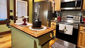 A kitchen with wooden cabinets, stainless steel appliances, and a unique island with a kettle. - One-of-a-kind historic getaway, where timeless charm meets modern fun & comfort. (Front Royal)