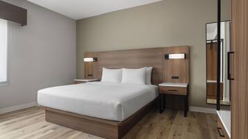 Ein modernes Schlafzimmer mit einem großen Bett, einem Holzkopfende, Nachttischen und einem Spiegel.