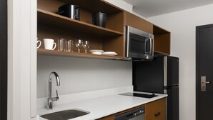 A modern kitchen with a built-in dishwasher, a stainless steel sink, and a microwave above the counter.