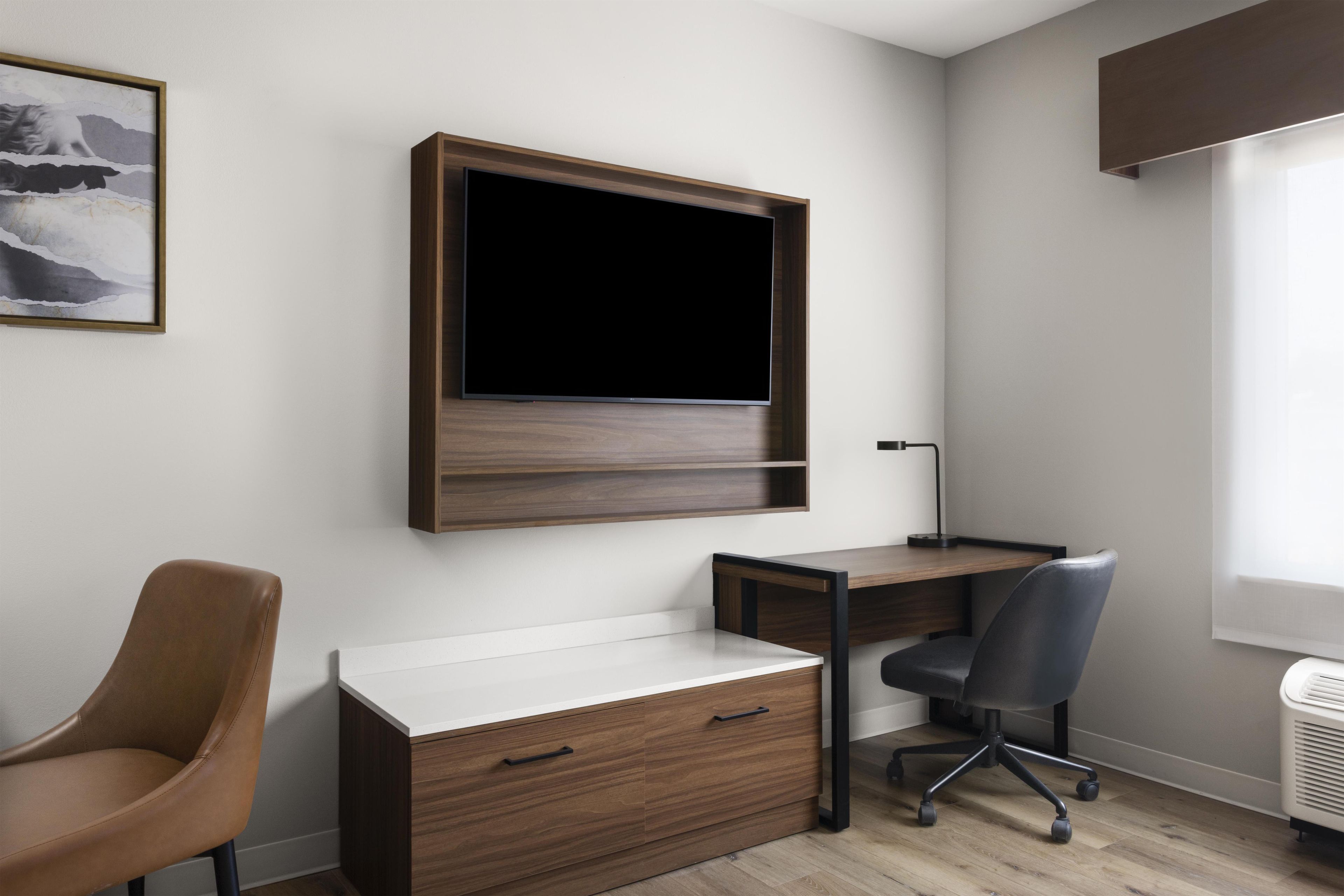 A modern office space with a desk, chair, and a mounted TV.
