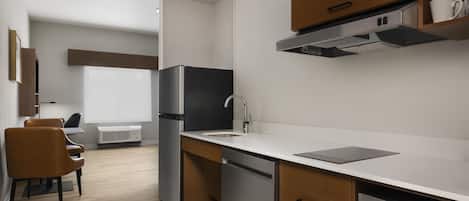 A modern kitchen with a built-in dishwasher, a stainless steel refrigerator, and a microwave.