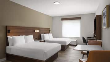 A hotel room with two beds, a desk, a chair, and a large window.