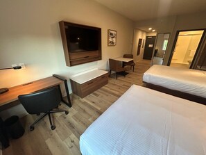 A hotel room with a desk, chair, two beds, a TV, and a small table. - @HOME by Best Western McDonough Atlanta South (McDonough)