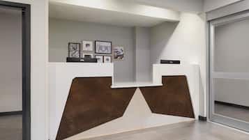 A reception desk with a modern design, featuring a wooden accent and framed artwork on the wall.