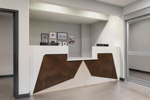 Una recepción con diseño moderno, que incluye detalles de madera y obras de arte enmarcadas en la pared.