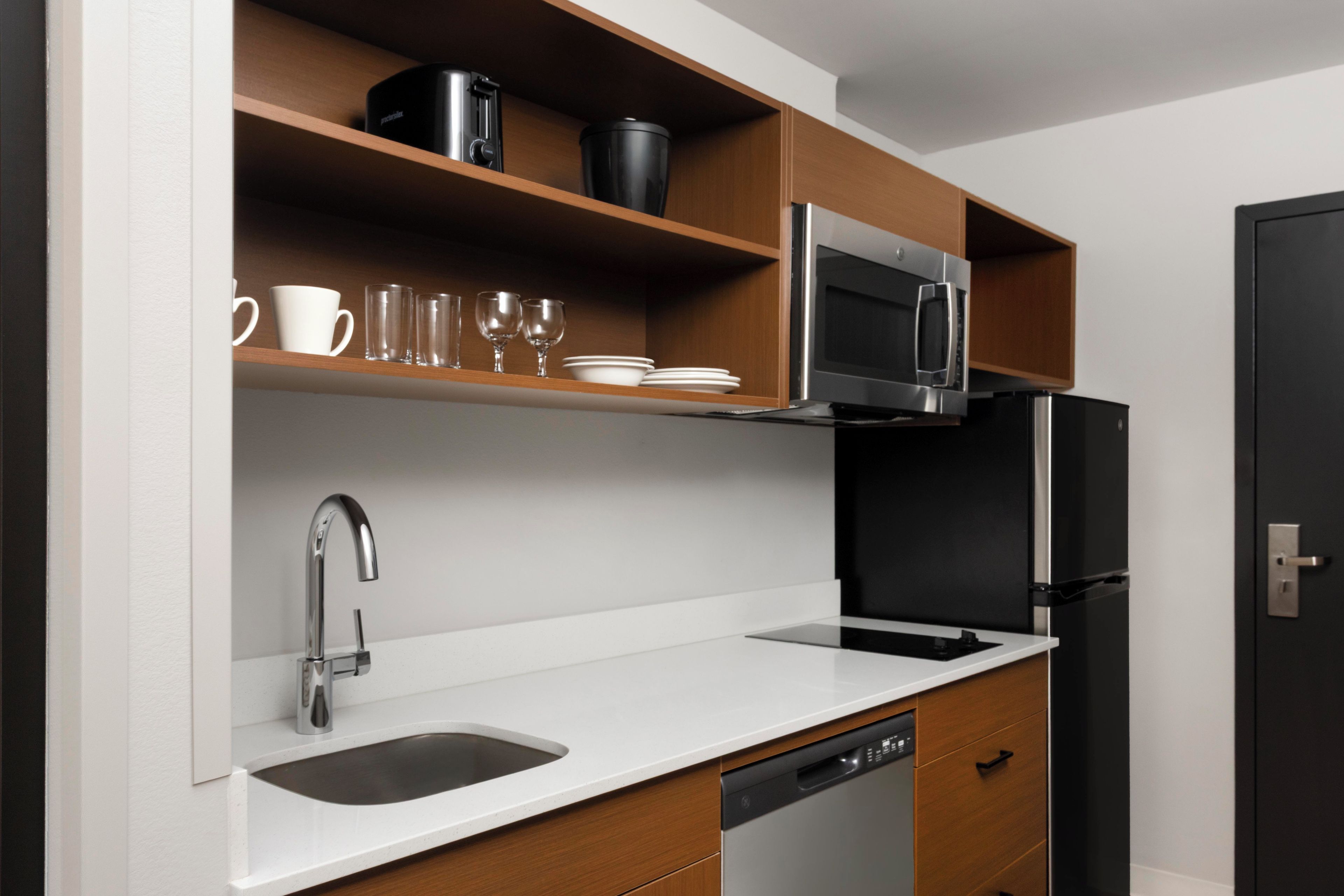 A modern kitchen with a stainless steel sink, a dishwasher, a microwave, and a refrigerator.