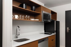 Uma cozinha moderna com uma pia de aço inoxidável, lava-louças, micro-ondas e geladeira.