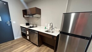 A modern kitchen with a stainless steel refrigerator, a built-in oven, and a dishwasher. - @HOME by Best Western McDonough Atlanta South (McDonough)