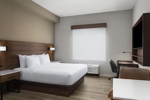 A hotel room with a large bed, bedside tables, a desk, a chair, and a TV. - @HOME by Best Western McDonough Atlanta South (McDonough)