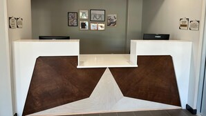 A reception desk with a modern design, featuring two computer stations and framed artwork on the wall. - @HOME by Best Western McDonough Atlanta South (McDonough)