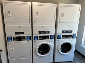 A row of stacked laundry machines in a commercial setting. - @HOME by Best Western McDonough Atlanta South (McDonough)