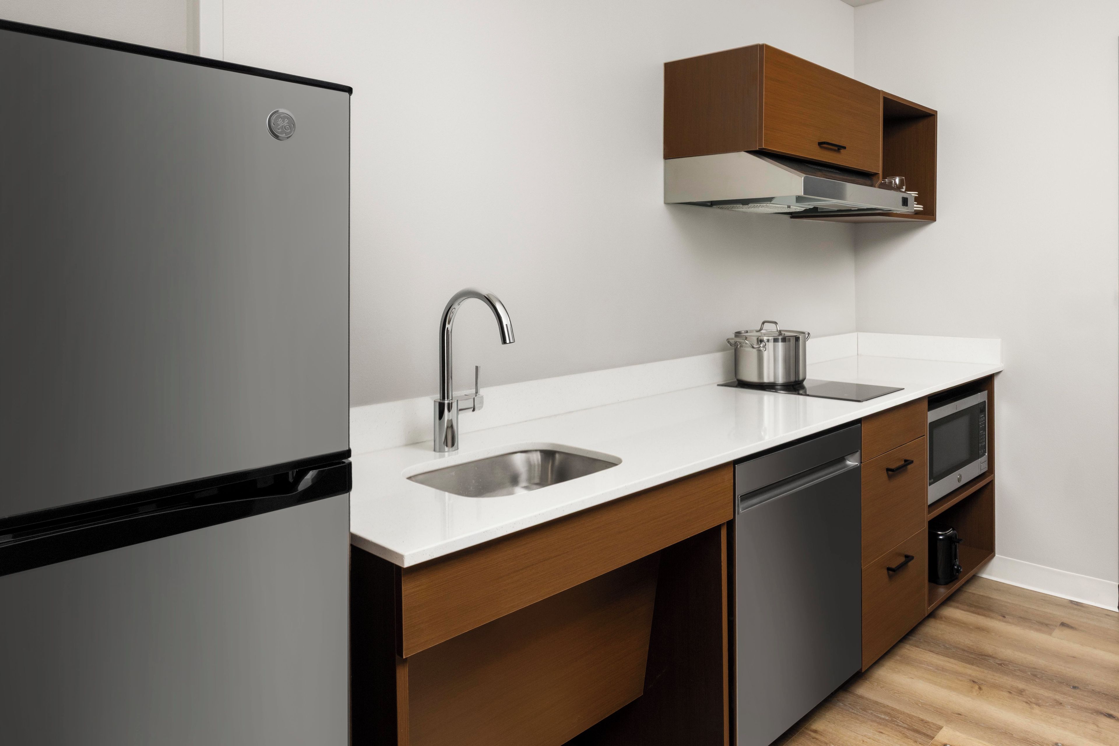 Une cuisine moderne équipée d’un réfrigérateur en acier inoxydable, d’un évier, d’une cuisinière et de meubles de rangement en bois.