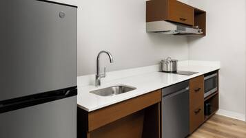 Une cuisine moderne équipée d’un réfrigérateur en acier inoxydable, d’un évier, d’une cuisinière et de meubles de rangement en bois.