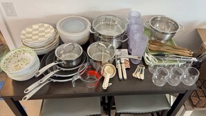 Ein Tisch mit Geschirr, darunter Teller, Schüsseln, Töpfe, Messbecher und Besteck.