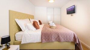 A neatly made bed with pillows, a bedside lamp, a TV on the wall, and a window with blinds. - Luxury Flat in Split City Center 15 min walk from Ferry Port and Beach (Split)