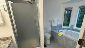 Ein Badezimmer mit Dusche, Toilette, Badewanne und einem Fenster.