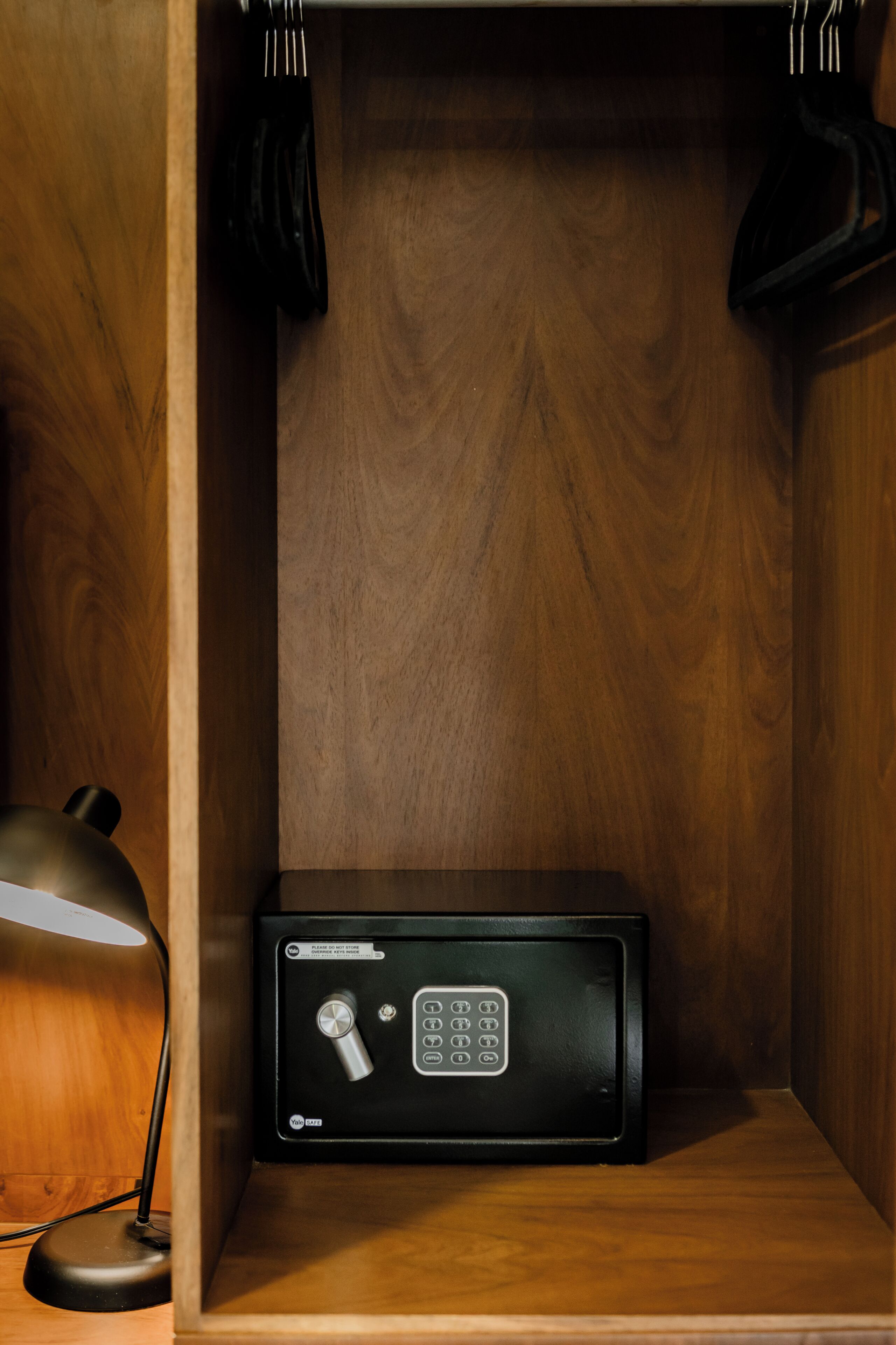 A wooden cabinet with a black safe, a desk lamp, and a black hanger.