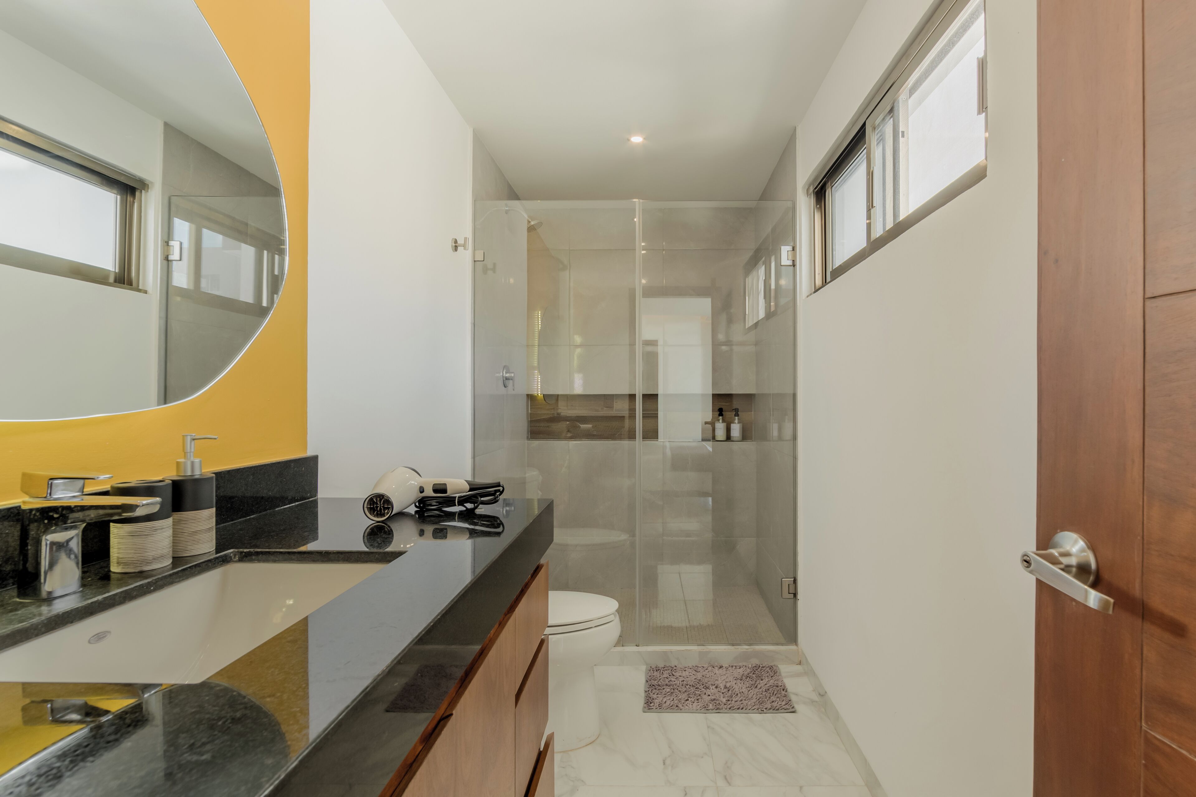 A modern bathroom with a glass shower enclosure, a toilet, and a vanity with a mirror.