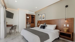 A modern bedroom with a large bed, a desk, a chair, a TV, and a wooden headboard.