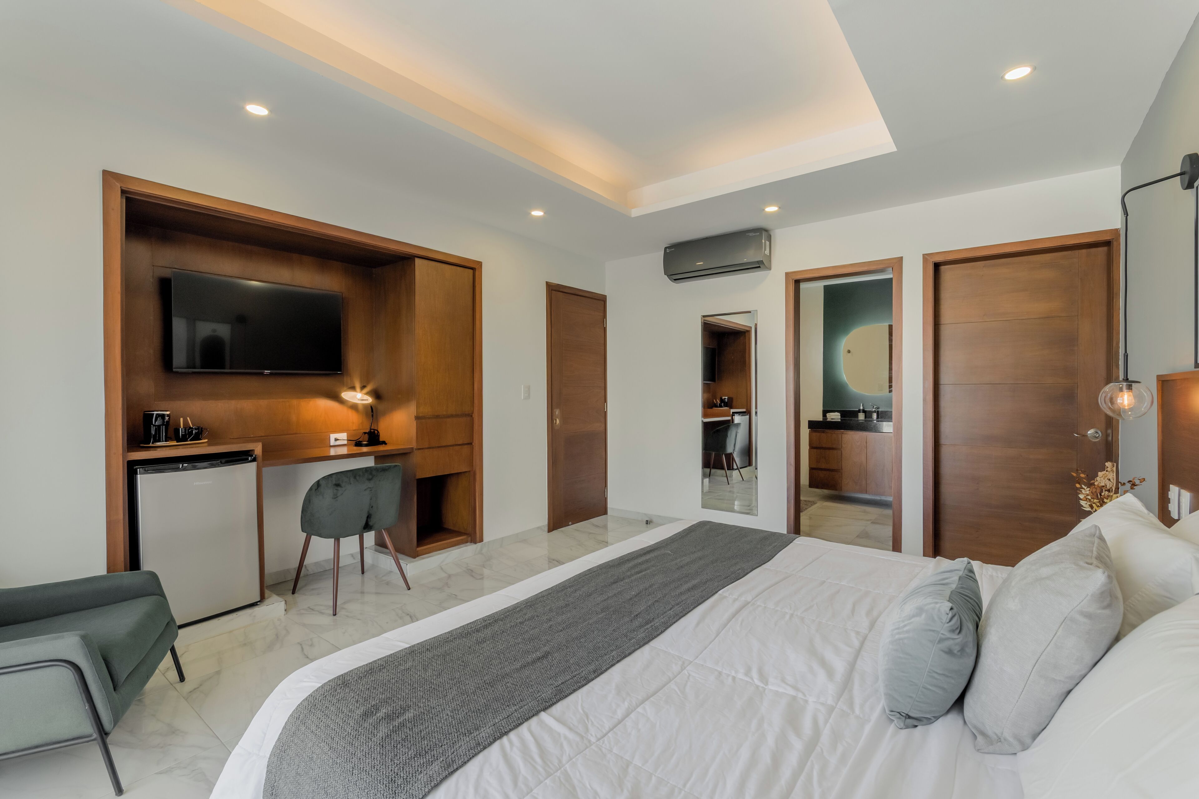 A modern hotel room with a bed, desk, chair, and a TV.